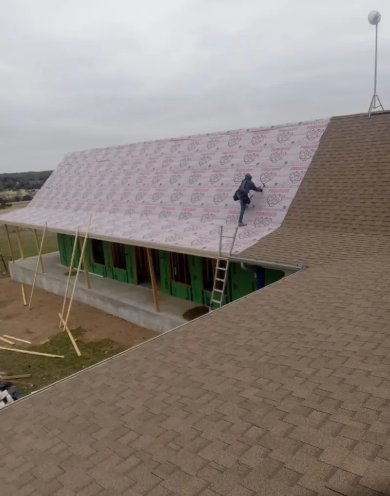 Worker preparing underlayment for a metal roof installation in Anderson Creek